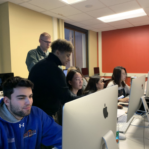 Photo of students and instructors inside a media lab classroom.